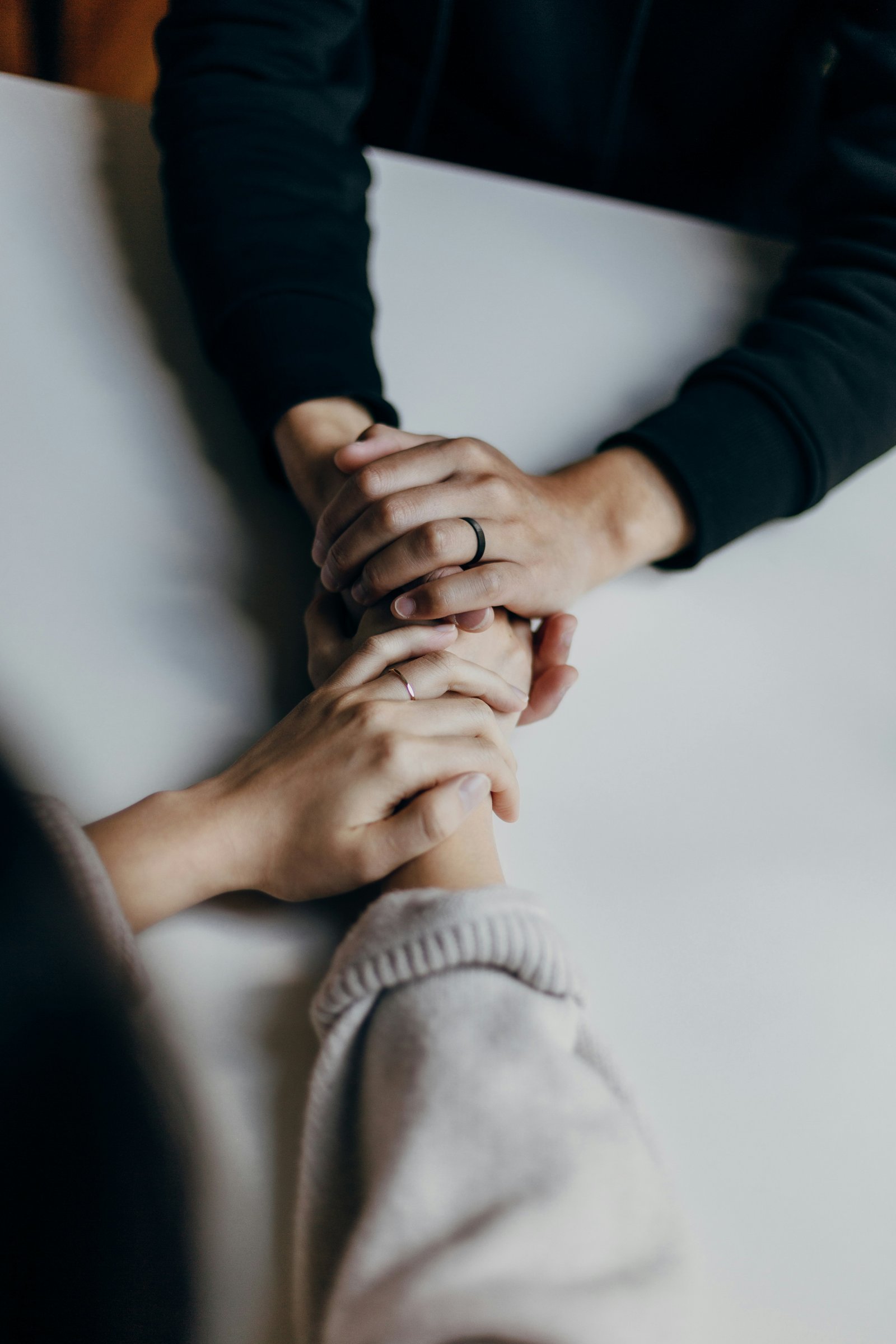 Two people holding hands gently across a table in support