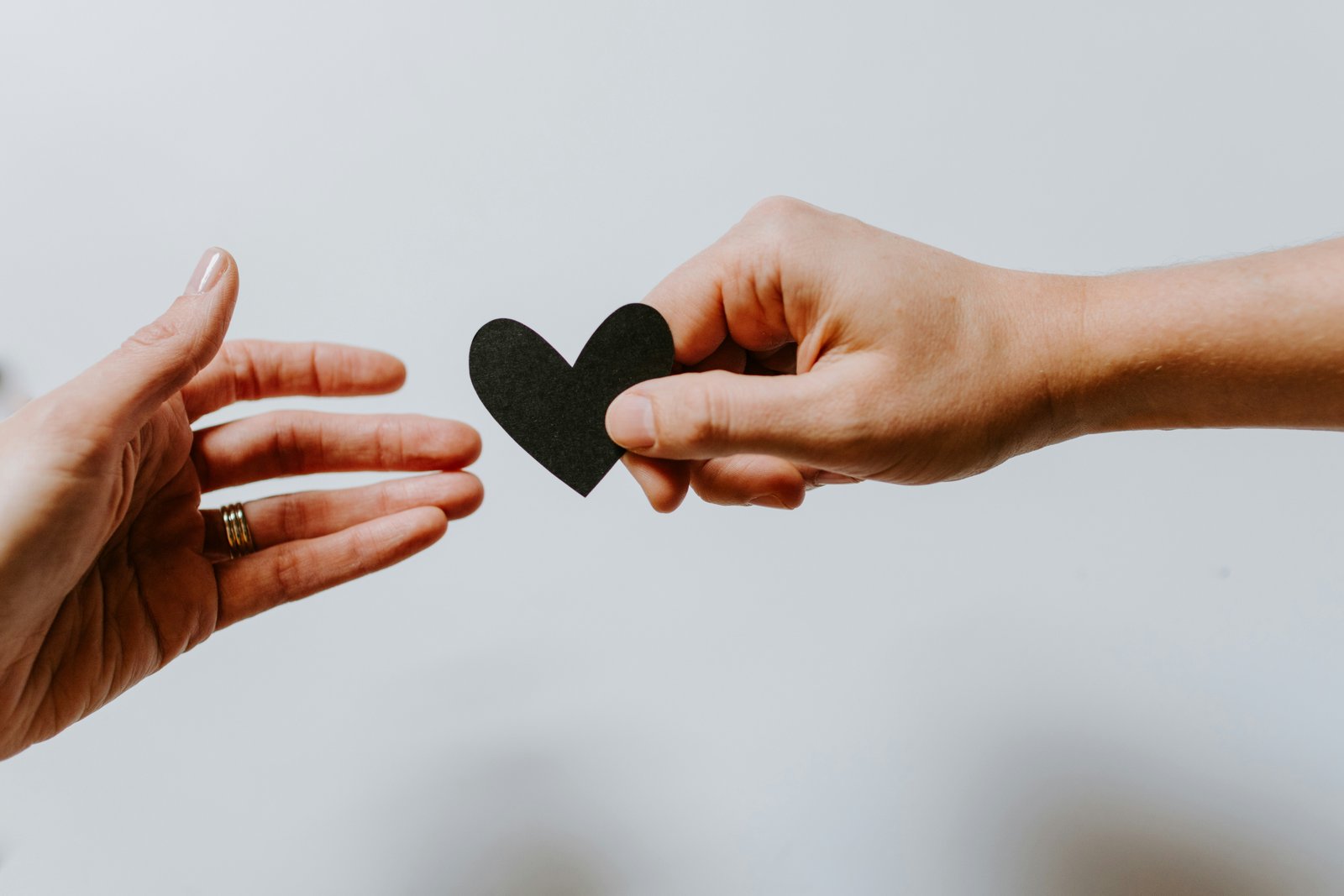 A hand offering a paper heart to another